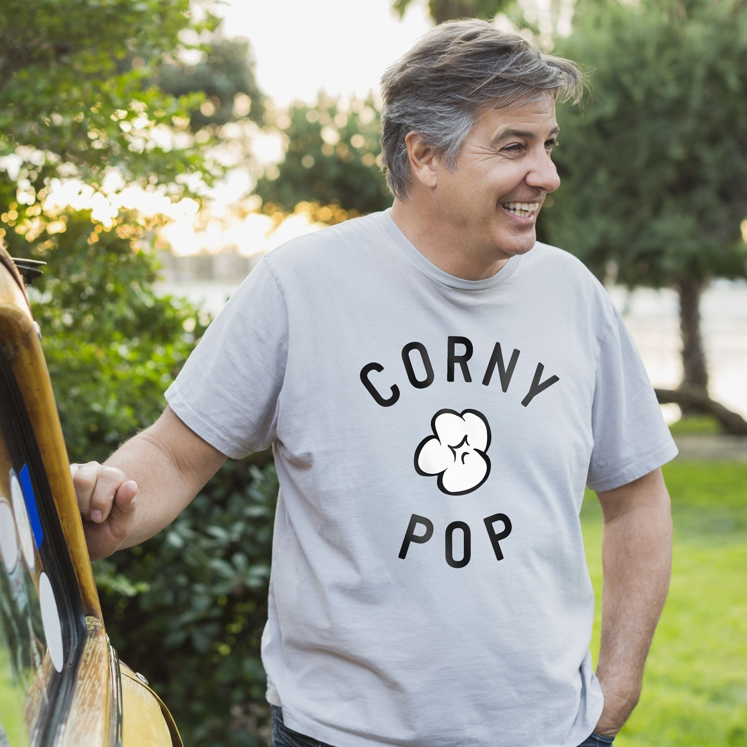 Dad t-shirts mens World's Greatest Dud corny popcorn design on man standing by car.